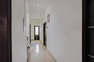 a hallway with white walls and a white tile floor at Super Hotel O Golden Imperial in Noida