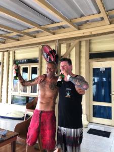 two men are drinking bottles of wine in a room at Jenny's Bamboo Surf Camp in Karbang