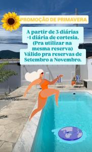 a poster of a woman jumping into a swimming pool at Recanto com piscina em Caraguatatuba - São Sebastião in Caraguatatuba