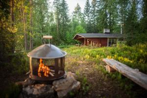 eine Feuerstelle vor einer Blockhütte in der Unterkunft Putkola Cottage Finland in Virasoja