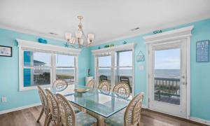 Un comedor con una mesa de cristal y sillas. en Beach Dream, en Holden Beach