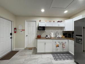 Una cocina con gabinetes blancos y un refrigerador. en Sunshine Nest, en Lehigh Acres