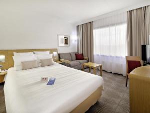 a hotel room with a large white bed and a couch at Novotel Katowice Centrum in Katowice +204 photos