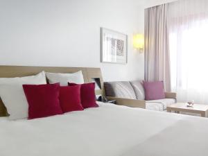 a bedroom with a large bed with red and purple pillows at Novotel Katowice Centrum in Katowice