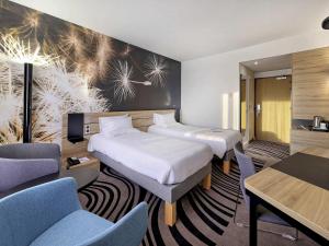 a hotel room with two beds and chairs at Novotel Katowice Centrum in Katowice