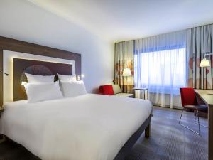 a hotel room with a large white bed and a desk at Novotel Katowice Centrum in Katowice +185 photos