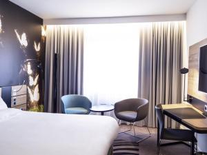 a hotel room with a bed and a desk and chairs at Novotel Katowice Centrum in Katowice +185 photos