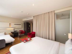 una camera d'albergo con due letti e una sedia rossa di Mercure Warszawa Grand a Varsavia