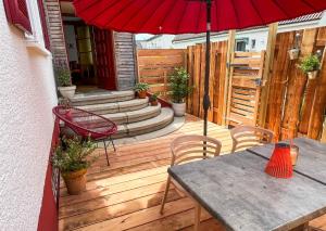 una terrazza in legno con tavolo e ombrellone rosso di Hacienda Flats - Wunderschöne Ferienwohnungen am Seewald a Friedrichshafen