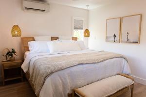 a white bedroom with a large bed and a window at Pualei Beach House in Lahaina