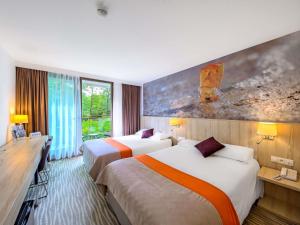 a hotel room with two beds and a large window at Mercure Gdańsk Posejdon in Gdańsk