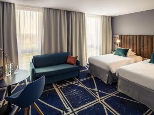 une chambre d'hôtel avec deux lits et une chaise dans l'établissement Hotel Mercure Poznań Centrum, à Poznań 156 autres photos