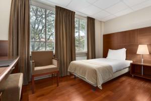 a hotel room with a bed and a chair at NH Eindhoven Conference Centre Koningshof in Veldhoven