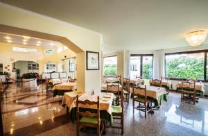 un restaurante con mesas, sillas y ventanas grandes en Hotel Lido La Perla Nera, en Stresa