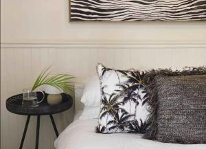a bed with a pillow and a table with a drink on it at Tosca Elegant Merewether Beach House with Pool in Merewether