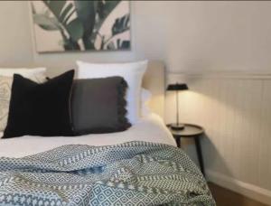 a bedroom with a bed with black and white pillows at Tosca Elegant Merewether Beach House with Pool in Merewether