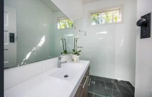 a bathroom with a sink and a mirror at Tosca Elegant Merewether Beach House with Pool in Merewether +42 photos