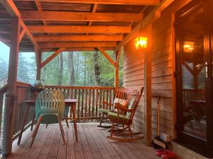 a porch of a cabin with chairs and a table at Deer View Cabin - Woodland, beaches and Hot tub in Hull