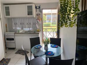 a kitchen with a glass table and chairs and a kitchen with a window at Flat no Condomínio Monte Castelo ao lado da área de lazer, Gravatá-PE in Gravatá