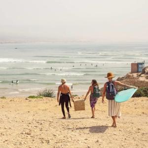 a group of three people walking on the beach at Immeuble ANAKHIL appartement surf in Tamraght Ouzdar
