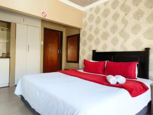 ein Schlafzimmer mit einem großen weißen Bett und roten Kissen in der Unterkunft Tokelo Guesthouse Emalahleni in Witbank + 111 Fotos
