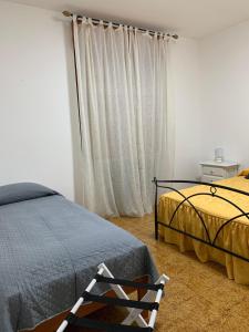 1 dormitorio con 2 camas y una silla junto a una ventana en La Casa di Mia, en Vesime