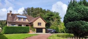 a house with a car parked in the driveway at Tamaris, Villa avec très grand jardin in Cucq