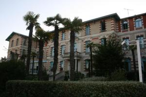 a building with palm trees in front of it at Résidence de Tourisme Vacances Bleues Villa Regina in Arcachon