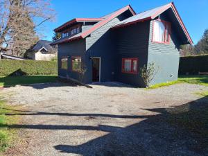 una casa negra con techo rojo en Los Panguis, en Villa La Angostura