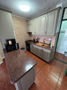 eine Küche mit weißen Schränken und einer Spüle in der Unterkunft Holiday Home Parque Azul Playa La Arena FREE WIFI in Puerto de Santiago