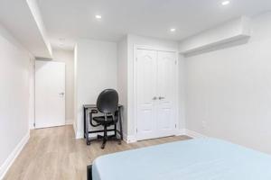 リッチモンドヒルにあるCozy 1BR Lower Level Walking distance to shopsの黒い椅子と白いベッドのある寝室