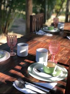 a wooden table with plates and wine glasses on it at Restaurante e Pousada Mandacaru Abacate in Campestre +47 photos