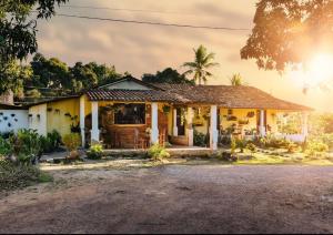 a house with a palm tree in front of it at Restaurante e Pousada Mandacaru Abacate in Campestre