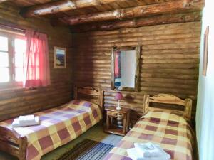 a bedroom with two beds in a log cabin at Cabañas La Brama in Aluminé