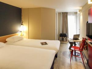 a hotel room with two beds and a laptop on a table at ibis Brest Kergaradec in Brest +50 photos