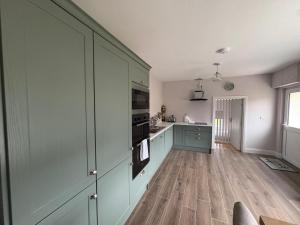 a kitchen with green cabinets and a wooden floor at Country Escape in Cloneen