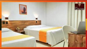 a hotel room with two beds and a laptop on a desk at Hotel Bellavista in Paulo Afonso
