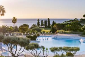 une piscine avec des arbres et l'océan en arrière-plan dans l'établissement Cozy Apartment in Agay with Stunning Views, à Agay