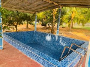 a swimming pool with a blue tile floor and trees at Rooms trincomalee in Trincomalee