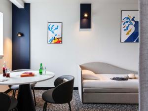 a room with a table and a couch and a table and chairs at Hotel ibis Rennes Centre Gare Sud in Rennes
