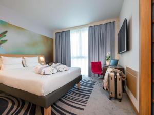 a hotel room with a bed and a suitcase at Novotel Milano Malpensa Aeroporto in Cardano al Campo +148 photos