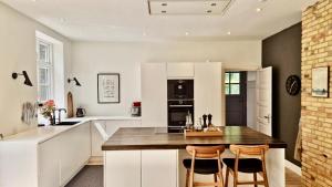 a kitchen with white cabinets and a table and chairs at Birkelund1927 in Dannemare