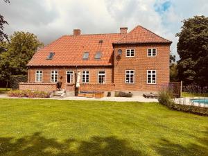 a large brick house with a pool in the yard at Birkelund1927 in Dannemare