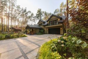 a large house with a patio in the woods at Villa Aleksandrow SPA in Aleksandrów