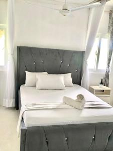 a bed with a black headboard with a towel on it at vii homes in Watamu +28 photos