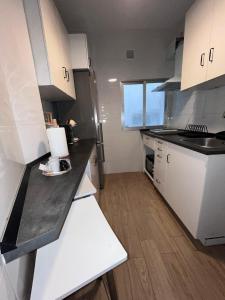 a kitchen with white cabinets and a black counter top at El Atelier in Alcalá de Henares +3 photos