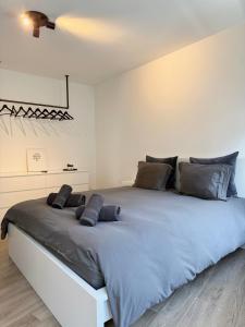 a white bedroom with a large bed with gray pillows at Appartement au coeur de Spa avec parking privé in Spa