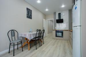 una cucina con tavolo, sedie e frigorifero di 1 комнатная квартира в новом ЖК Панорама Парк по улице Темирбаева 50 a Qostanay