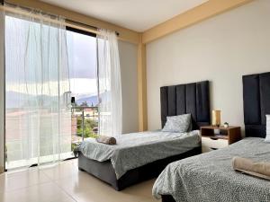 a bedroom with two beds and a large window at Alojamiento Bilbao in Quillacollo
