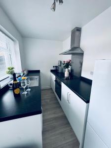 ホワイトヘイブンにあるHolly Terrace - 2 Bedrooms - Sleeps 3のキッチン(黒いカウンタートップ、白いキャビネット付)